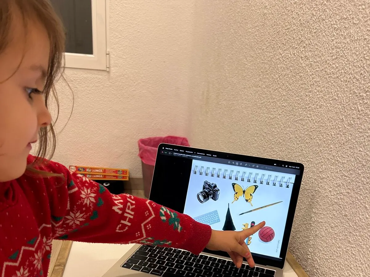 Una niña señala una lámina de imágenes en la pantalla del portátil durante una prueba de vocabulario